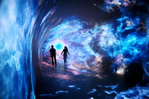 两名观众走在蓝色星云与光环影像环绕的沉浸式数字空间中