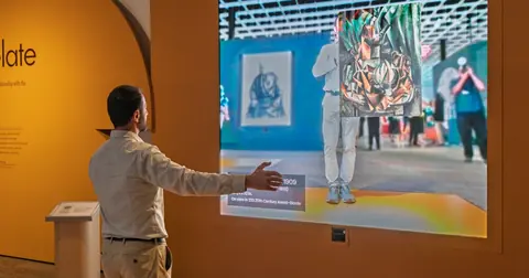 观众在 Cleveland Museum of Art 的 ArtLens Reimagined 互动数字墙前体验馆藏图像
