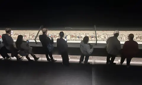 大英博物馆贝叶挂毯展中,观众沿低照度展柜排队观看长卷