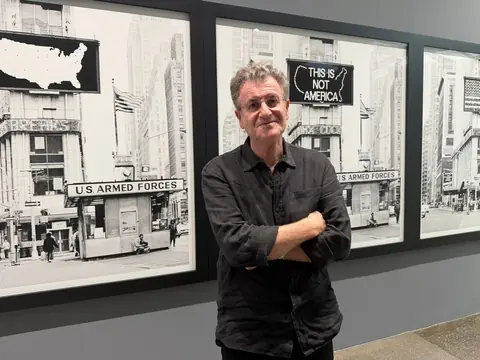 艺术家 Alfredo Jaar 站在纽约《A Logo for America, 1987》展览空间内