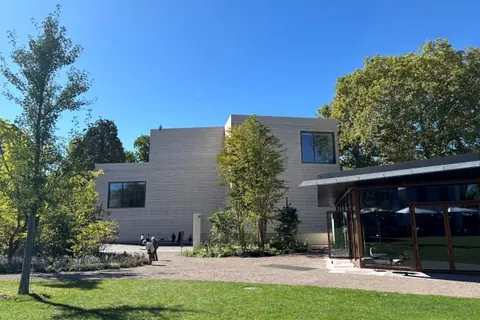 阳光下的贝耶勒基金会新夯土混凝土建筑,前景可见树木