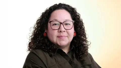 Mary Deleary 的肖像,她佩戴红色耳饰并身着深色衬衫