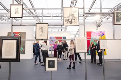 Frieze London 2026 的 White Cube 展位,金属结构上悬挂纸上作品,观众在其后通行