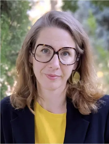 身穿蓝色外套、佩戴眼镜的 Hélia Paukner 肖像